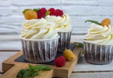 Peynir kremalı ve böğürtlenli çikolatalı kekler beyaz tabakta. Yakın plan..