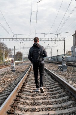 Sırt çantalı bir gezgin tren yolu boyunca yürüyor..
