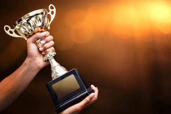 Mão segurando um troféu de ouro — Fotografia de Stock