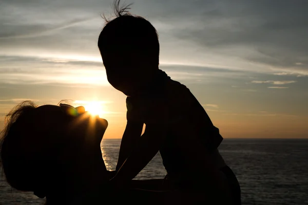 Μητέρα και το μικρό γιο σιλουέτες στην παραλία στο ηλιοβασίλεμα — Φωτογραφία Αρχείου