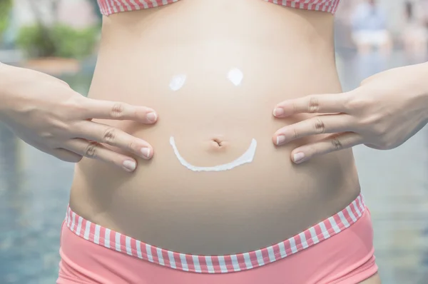 Sahne glückliches Smiley-Gesicht auf dem Bauch einer Schwangeren Stockbild