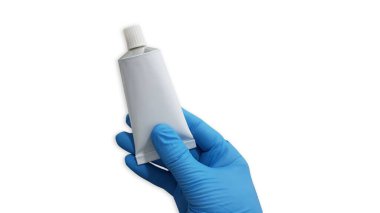 Beyaz arka planda boş beyaz merhem tüpü tutan mavi tıbbi eldiven verin.