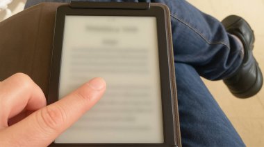 Dijital kitapla rahatlarken insan parmağı okuyucu ekranına dokunuyor