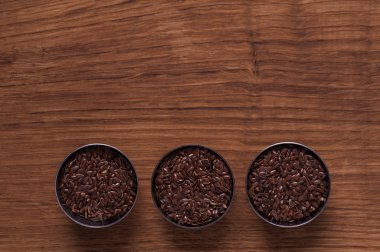 kahverengi ahşap masa üzerinde metal kabın içinde keten tohumu