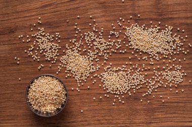 ahşap masa üzerinde metal kapta darı