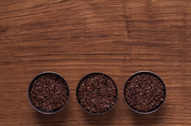 kahverengi ahşap masa üzerinde metal kabın içinde keten tohumu