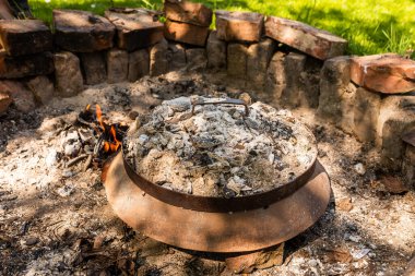 Photo of Cooking traditional dalmatian, croatian, bosnian dish called peka. Meat, potatoes and vegetables in pot and covered with hot charcoal and ash. Balkan food.