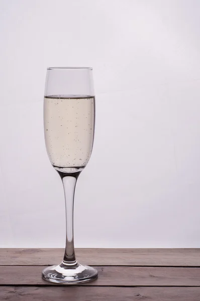 Champagne glas op houten tafel tegen witte achtergrond — Stockfoto