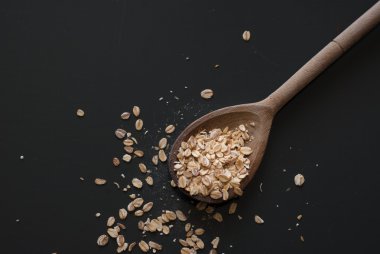 üzerinde koyu ahşap masa üstünde tahta kaşık yulaf gevreği