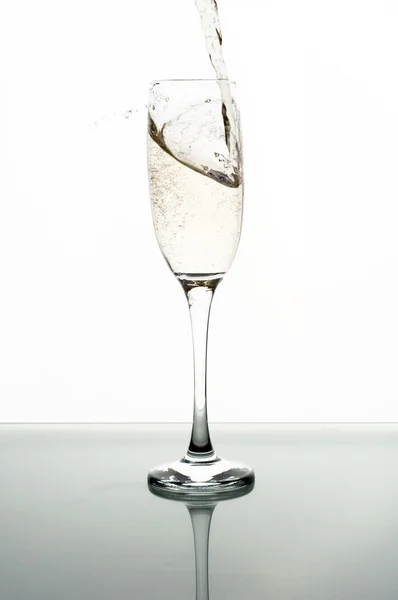 Champagner in Glas auf weißem Hintergrund gießen — Stockfoto