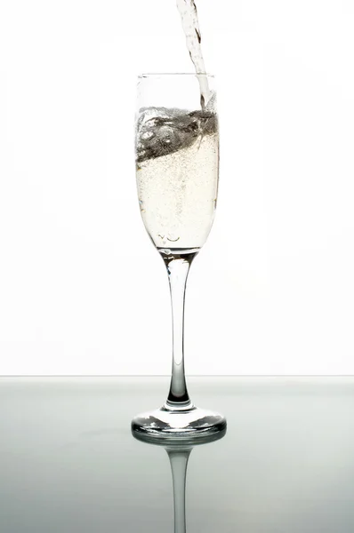 Derramando champanhe em vidro no fundo branco — Fotografia de Stock