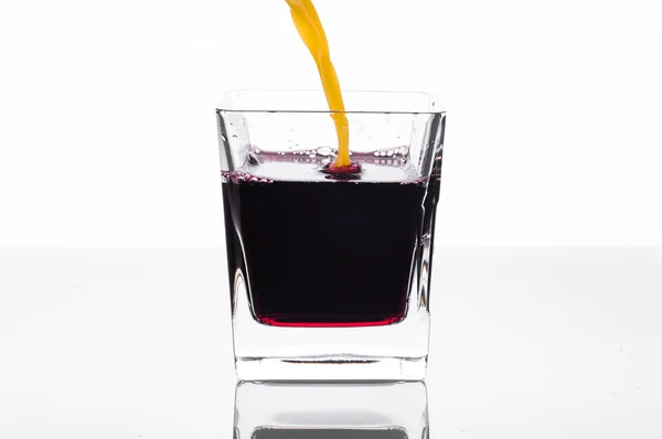 Zumo de naranja vertiendo en el vaso con jugo de grosella negra —  Fotos de Stock