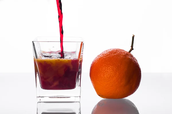 Suco de groselha-preta derramando em vidro com suco de laranja — Fotografia de Stock