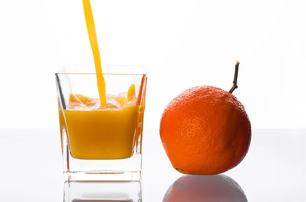 Suco de laranja derramando em vidro — Fotografia de Stock
