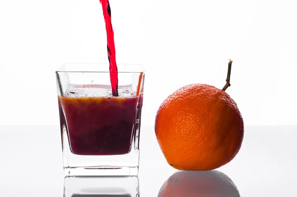 Suco de groselha-preta derramando em vidro com suco de laranja — Fotografia de Stock