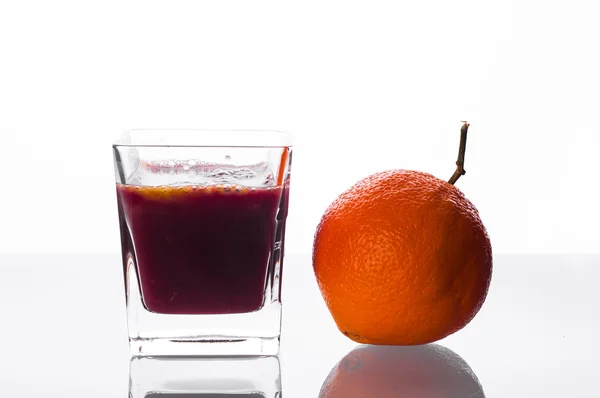 Jugo de grosella negra vertiendo en el vaso con jugo de naranja —  Fotos de Stock
