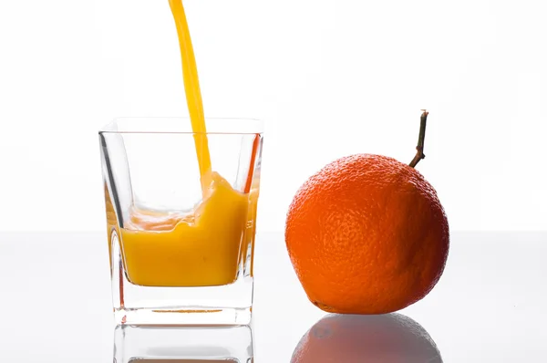 Suco de laranja derramando em vidro — Fotografia de Stock