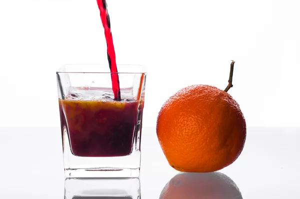 Сок черной смородины наливается в стакан апельсиновым соком — стоковое фото