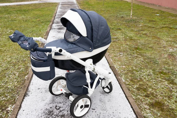 Kinderwagen op een besneeuwde stoep. Dagelijkse wandelingen in de frisse lucht. Tijd doorbrengen met uw baby op een witte sneeuwwitte winterdag. — Stockfoto