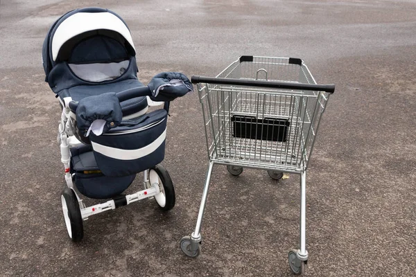 Порожній продуктовий візок з супермаркету на вулиці та дитячий візок. Концепція . — стокове фото