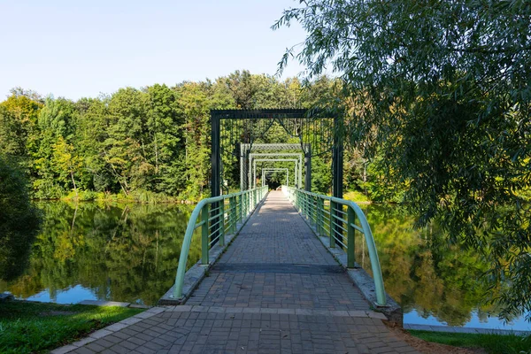Pedestrian bridge over the river against the background of the river and trees and reflection in the water.