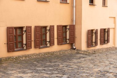 Eski bir evin tuğla duvarındaki pencereler. Yaya yolunun arka planındaki eski bir binanın cephesi..