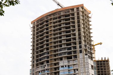 İnşaat halindeki bir evin arka planında vinç var.