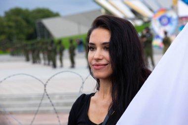 Minsk, Belarus - 20 Eylül 2020 Belarus 'ta barışçıl protestolar. Askeriyenin arka planında bayrağı olan bir kızın portresi, asker. Seçici odak.