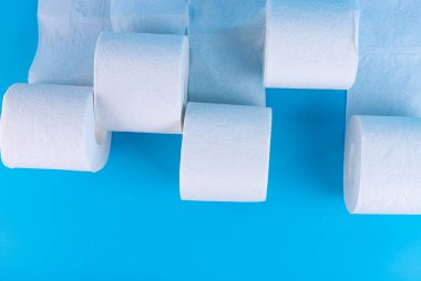 Mavi arka planda beyaz tuvalet kağıdı ruloları metin ve reklam için yer var..