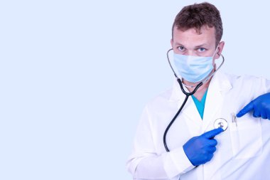 Tıbbi önlüklü yakışıklı bir doktor yan duruyor ve steteskop ile yazı için yer tutuyor. Tıbbi konsept.