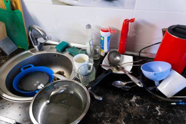 Metal lavaboda bir yığın kirli bulaşık ve masanın üzerine dökülüyor. Kahvaltıdan sonra mutfak, öğle yemeği, akşam yemeği. Temiz bulaşık konsepti.