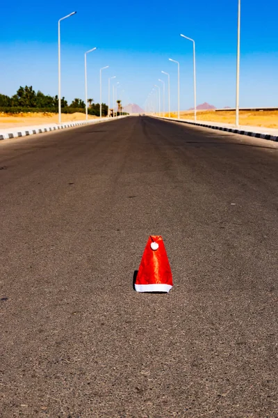 The beginning or end of the Christmas holidays, a lost or thrown Santa hat lies on the highway. Selective focus.
