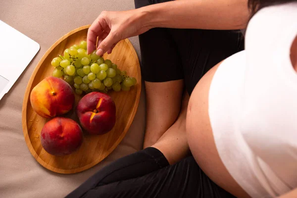 Hamile Bir Kadın Elinde Meyve Tabağıyla Kanepede Oturur Yüksek Kalite — Stok fotoğraf