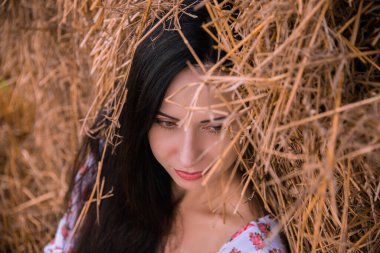 Saman arka planında yaz elbisesi içinde güzel siyah saçlı kız, doğa..