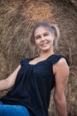 Saman arka planında güzel, genç, sarışın bir kız, doğa. Ülke biçimi.