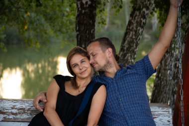 Güzel, mutlu çift doğanın arka planında iyi eğlenceler. Gömlekli yakışıklı bir adam gülümseyen sarı saçlı bir kıza nazikçe sarılıyor. Yaşam tarzı ve seyahat konsepti.