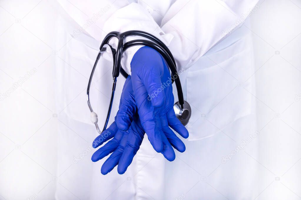 Medical ethics concept, bound hands. The doctor holds a stethoscope in his hands.