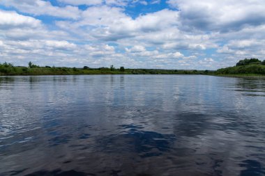 Parlak mavi gökyüzü ve bulutlarıyla yaz nehri