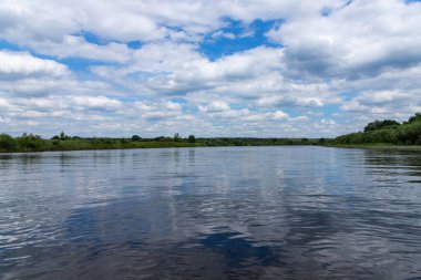 Parlak mavi gökyüzü ve bulutlarıyla yaz nehri