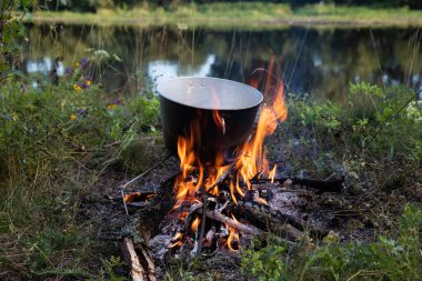 Açık bir kamp alanındaki yangında mutfak gereçleri saksısı.