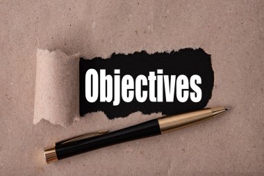 Yırtık kağıt ve metal kalemle yazılmış OBJECTIVES metni. İş stratejisi kavramları.