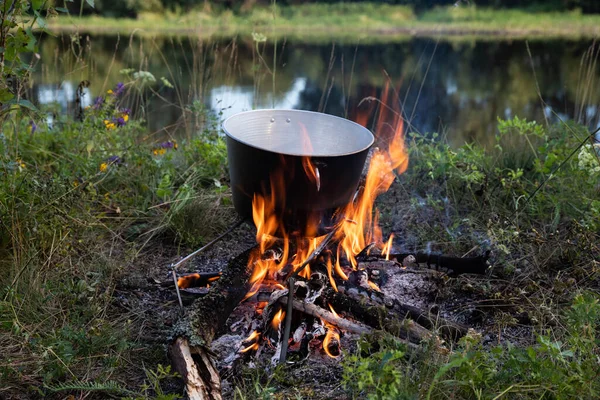 Açık bir kamp alanındaki yangında mutfak gereçleri saksısı.