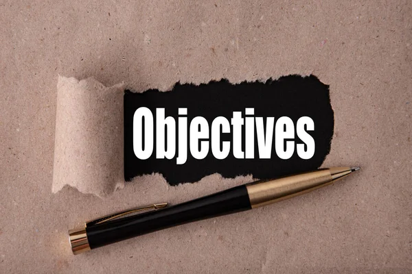 Yırtık kağıt ve metal kalemle yazılmış OBJECTIVES metni. İş stratejisi kavramları.