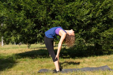 Kadın fitness eğitmeni yapar, yeşil bir parkta egzersiz yapar. Spor konsepti.