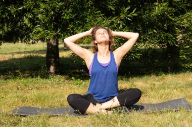 Kadın fitness eğitmeni yapar, yeşil bir parkta egzersiz yapar. Spor konsepti.