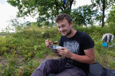 Gezgin nehir boyunca rafting yaparken kampta kahvaltı yapıyor..