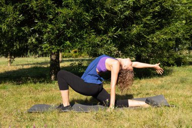 Kadın fitness eğitmeni yapar, yeşil bir parkta egzersiz yapar. Spor konsepti.