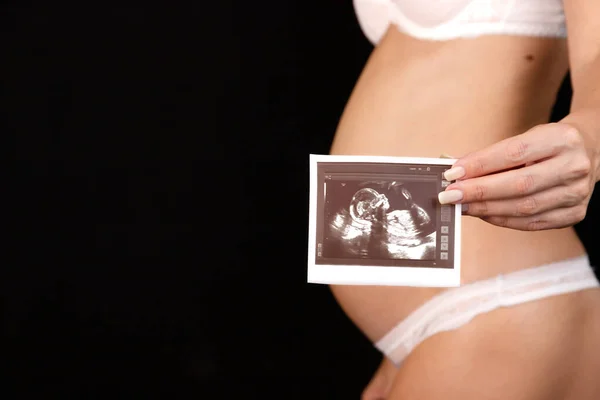 Beyaz Çamaşırlı Hamile Bir Kadın Karnının Önünde Ultrason Fotoğrafı Tutuyor — Stok fotoğraf