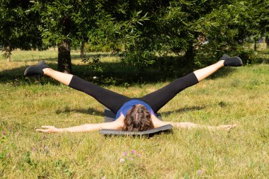 Kadın fitness eğitmeni yapar, yeşil bir parkta egzersiz yapar. Spor konsepti.