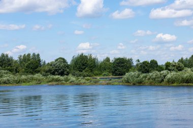 Parlak mavi gökyüzü ve bulutlarıyla yaz nehri
